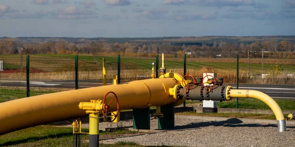 Big gas pipe - natural gas transport system. Transmission infrastructure coming from the ground, yellow pipes with a safety valve