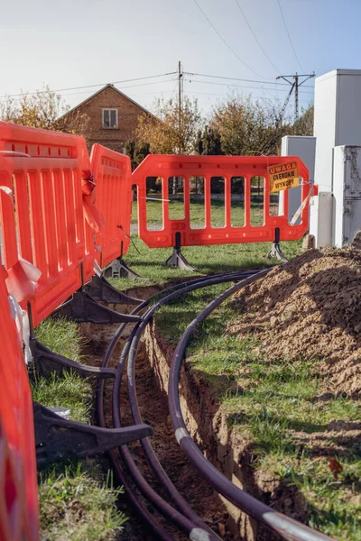 Yerdeki kalın bir elektrik kablosu bariyerin arkasındaki yüksek voltajlı direkte bir elektrik tüneli ve koruyucu çit.