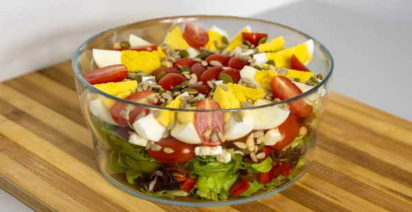 Çeyrek yumurtalı salata, domates, marul ve tahıllar tahtada.