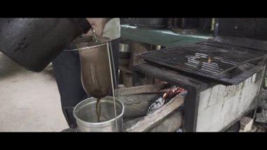 Köhne bir odun sobasında organik kahve yapmak için metal teneke kutuyu ısıtma suyuna yakın çekim. Bahia, Brezilya. Kış kavramı, soğuk, rahat, antika, sabah, kahve makinesi, retro. 4K