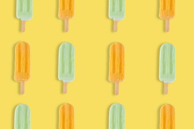 Colorful summer pattern. Mango and lemon popsicles on a yellow background.