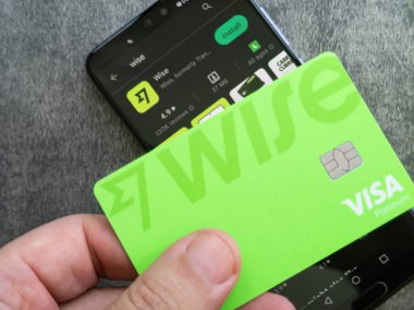 Ilheus Bahia , Brazil - 25 April 2023: Hand holding WISE (former transferwise ) fintech debit bank card. Green plastic card. Gray background. VISA Platinum logo on card.. clipart