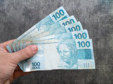 Brezilya 100 reais banknotuyla el ele tutuşuyorlar. Finans kavramı.