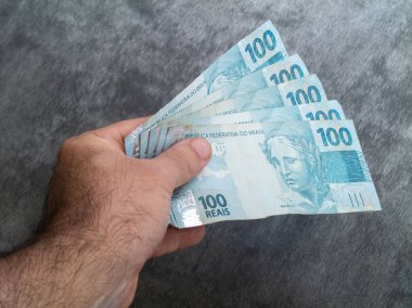 Brezilya 100 reais banknotuyla el ele tutuşuyorlar. Finans kavramı.