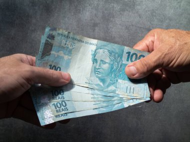 Brezilya 100 reais banknotuyla el ele tutuşuyorlar. Finans kavramı.