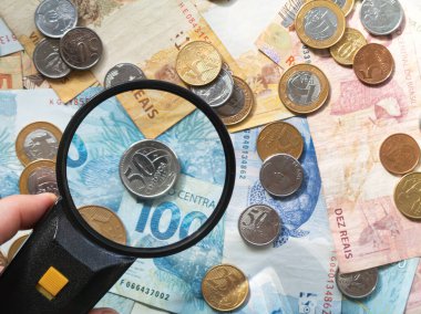 Brezilya para banknotları ve bozuk paralar üzerinde büyüteç. Finans kavramı.
