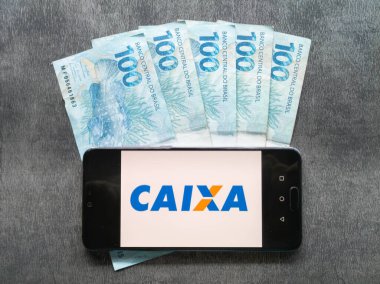 Bahia Brezilya, 02 Haziran 2023. Brezilya parasının bozuk paraları ve banknotları hakkında akıllı telefon ekranında Caixa β mica uygulaması.