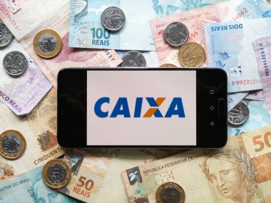Bahia Brezilya, 02 Haziran 2023. Brezilya parasının bozuk paraları ve banknotları hakkında akıllı telefon ekranında Caixa β mica uygulaması.
