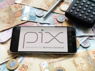 Bahia, Brezilya, 02 Haziran 2023. Brezilya parasının para ve banknotları üzerinde akıllı telefon ekranında Pix uygulaması.