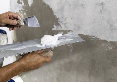 İşçi, sıva malası kullanarak duvarda alçı tabakası oluşturur..