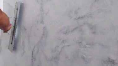 İşçi, sıva malası kullanarak duvarda alçı tabakası oluşturur.