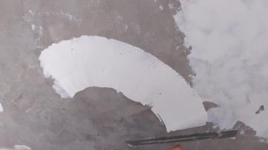 İşçi, sıva malası kullanarak duvarda alçı tabakası oluşturur.