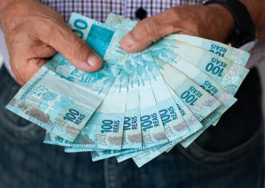 Brezilya parası işte. Brezilya 'nın gerçek banknotlarını tutan eller.