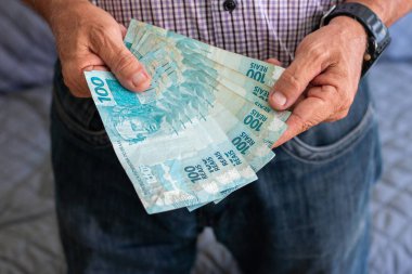 Brezilya 100 doları tutan adam Gerçek banknotlar.