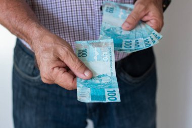 Bir adam Brezilya 'ya 100 gerçek banknot veriyor. Para, finans ve ödemeyi temsil ediyor..