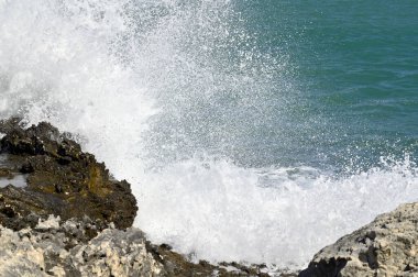 Dalgalar dalgalar dalgalı yeşil-mavi deniz ile kayalık kıyı şeridinde