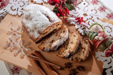 Çalınmış, tatlı Noel ekmeği taze pişmiş ve Noel temalı ahşap bir kesme tahtasının üzerine serilmiş..