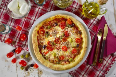 Mediterranean pizza with cherry tomatoes, olives, anchovies and capers cooked in a wood oven and with some ingredients near clipart