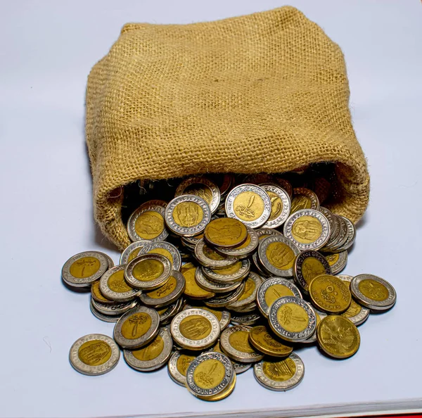 Burlap bag with Egyptian one-pound coins, isolated on a white background