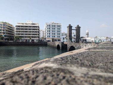 Deniz kenarındaki binaların göz kamaştırıcı bir silueti, berrak mavi gökyüzünün altında sakin bir plaj..