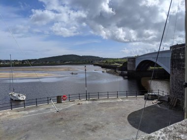 Nehir üzerinde köprüsü, bulutları ve mavi gökyüzü olan şehir silueti.