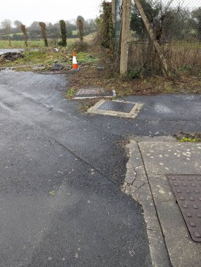 Tek bir trafik konisi, ıslanmış ve hasar görmüş bir Güney Galler manzarasındaki çitin arka planına karşı duruyor. Araştırma için mükemmel.