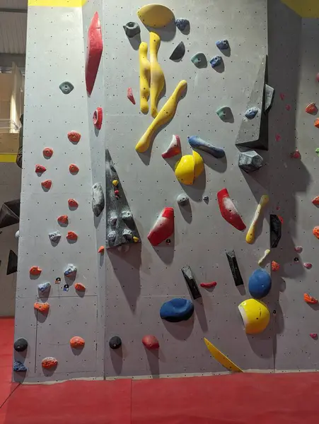 stock image Indoor rock climbing wall featuring colorful climbing holds in a gym setting. Suitable for fitness, exercise, and recreation activities.