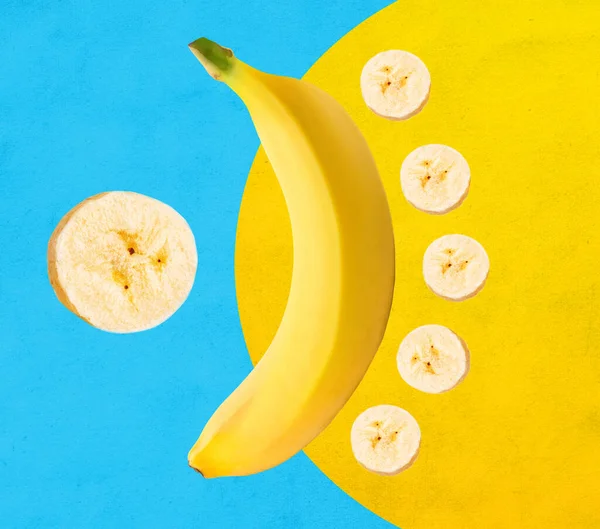Fresh yellow banana with banana slices isolated on blue and yellow background
