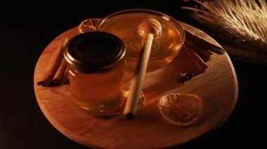 Healthy organic honey in a plate with wooden honey dipper top view on black background. Sweet honey healthy dessert Close up