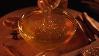 Healthy organic honey in a plate with wooden honey dipper top view on black background. Sweet honey healthy dessert Close up