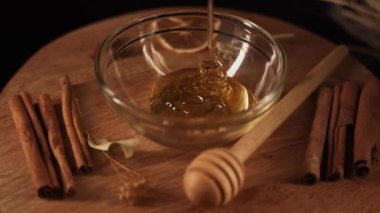 Healthy organic honey in a plate with wooden honey dipper top view on black background. Sweet honey healthy dessert Close up