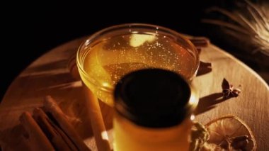 Healthy organic honey in a plate with wooden honey dipper top view on black background. Sweet honey healthy dessert Close up