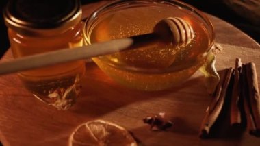 Healthy organic honey in a plate with wooden honey dipper top view on black background. Sweet honey healthy dessert Close up