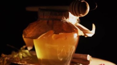 Healthy organic honey in a plate with wooden honey dipper top view on black background. Sweet honey healthy dessert Close up