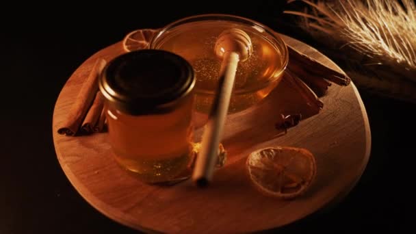 健康的有机蜂蜜在一个有木制蜂蜜切割机顶部观点黑色背景的盘子里 甜甜蜜蜜健康甜点 — 图库视频影像