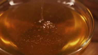 Healthy organic honey in a plate with wooden honey dipper top view on black background. Sweet honey healthy dessert Close up