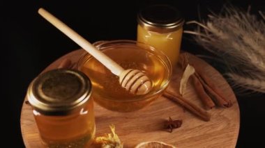 Healthy organic honey in a plate with wooden honey dipper top view on black background. Sweet honey healthy dessert Close up