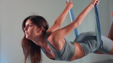 Attractive sexy girl doing sports and flying in air on stretch fabric Airo stretching or fly yoga. Active healthy lifestyle. 