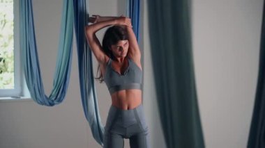 Attractive sexy girl doing sports and flying in air on stretch fabric Airo stretching or fly yoga. Active healthy lifestyle. 