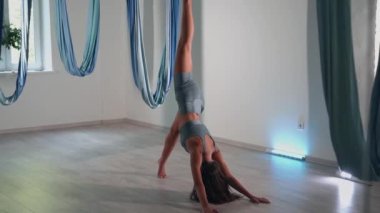 Attractive sexy girl doing sports and flying in air on stretch fabric Airo stretching or fly yoga. Active healthy lifestyle. 