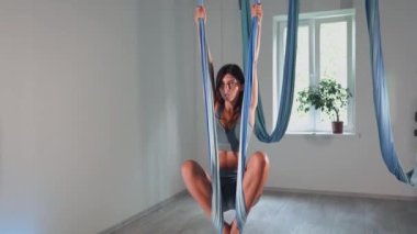 Attractive sexy girl doing sports and flying in air on stretch fabric Airo stretching or fly yoga. Active healthy lifestyle. 