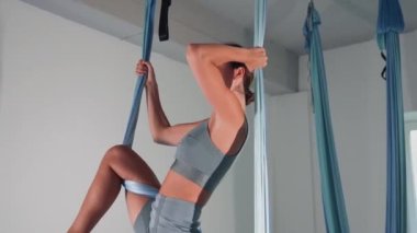 Attractive sexy girl doing sports and flying in air on stretch fabric Airo stretching or fly yoga. Active healthy lifestyle. 