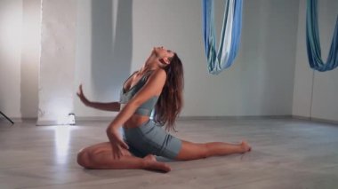 Attractive sexy girl doing sports and flying in air on stretch fabric Airo stretching or fly yoga. Active healthy lifestyle. 