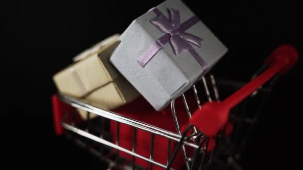 Winkelwagen Gevuld Met Diverse Kleuren Geschenkdozen Zwarte Achtergrond — Stockvideo