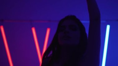 Ultraviyole ışıkta uzun saçlarıyla dans eden güzel bir kız.