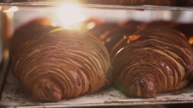 Kruvasanlar, ticari bir mutfakta kahvaltıda müşteriler için fırından çıktıktan sonra tepside. Fırında taze kruvasan satılıyor.