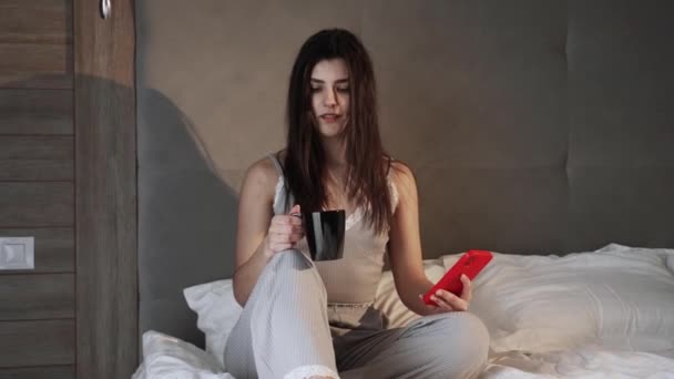 Happy Uśmiechnięta Kobieta Pomocą Smartfona Dinking Gorącej Kawy Rano Łóżku — Wideo stockowe