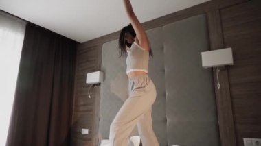 Yatak odasında yatakta dans eden bir kadın. Sağlıklı sabah konsepti.