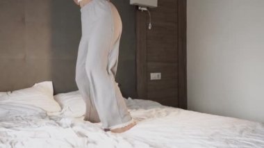 Yatak odasında yatakta dans eden bir kadın. Sağlıklı sabah konsepti.