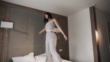 Yatak odasında yatakta dans eden bir kadın. Sağlıklı sabah konsepti.